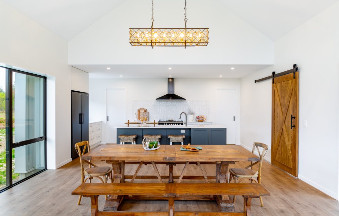 Architecturally designed rural home kitchen and dining area with barn door Cust